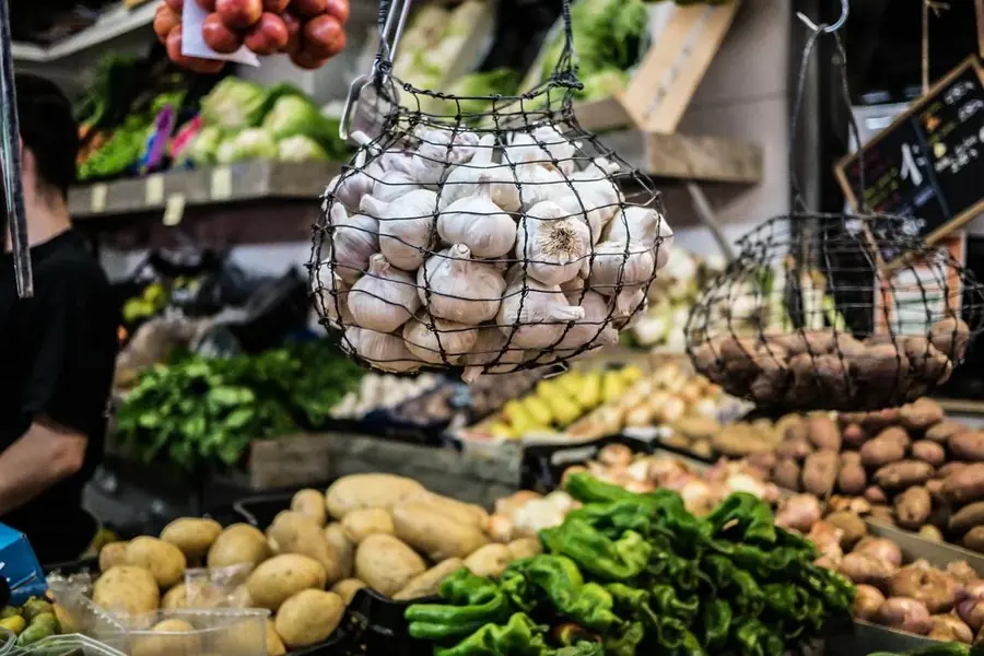 Wire basket of garlic hanging at a market stall with fresh vegetables in Golf del Sur