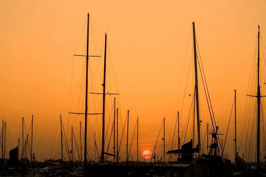 Sailboat masts silhouetted against orange sunset sky at Golf del Sur marina, Tenerife