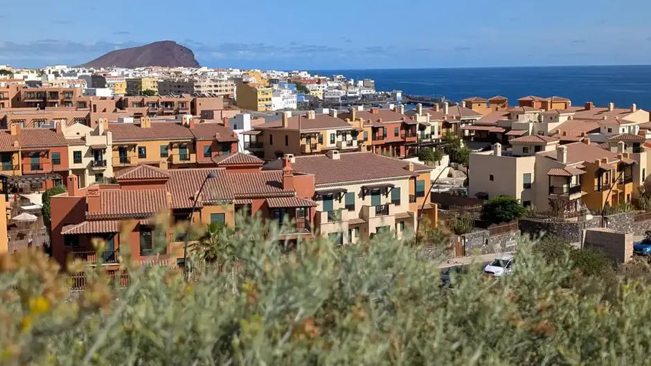 A scenic daytime view of the San Blas coastal town in Tenerife, with the Atlantic Ocean and Montaña Roja in the background