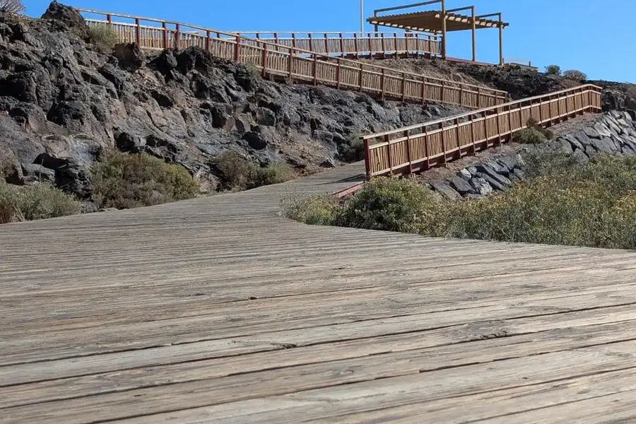 Wooden boardwalk promenade over volcanic rocks leading to a viewpoint, Golf del Sur, Tenerife