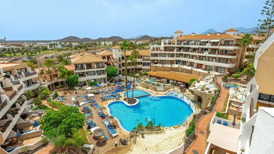 A view of the Parque Albatros resort in Tenerife, featuring the central swimming pool and apartments, where the owners' community (comunidad) is deciding the future of individual rentals (Viviendas Vacacionales, VV).