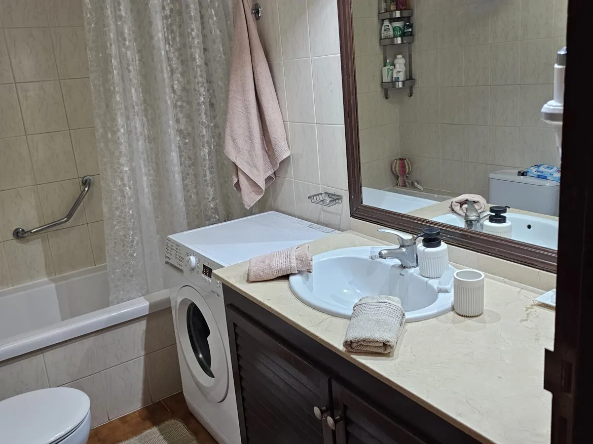 Bathroom with washer, sink, and bathtub.