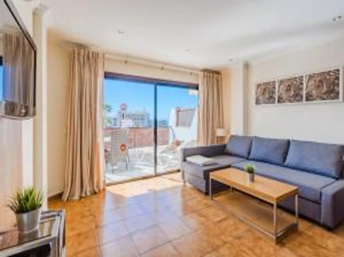 Bright living room with sofa, table, and balcony view.