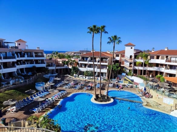 Resort pool area with lounge chairs and buildings.