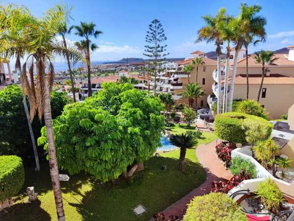 Tropical garden with palm trees and resort buildings.