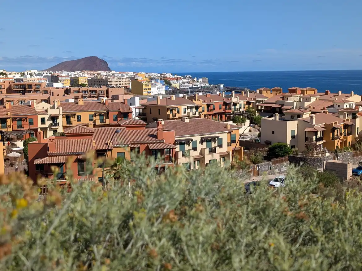 A scenic daytime view of the San Blas coastal town in Tenerife, with the Atlantic Ocean and Montaña Roja in the background