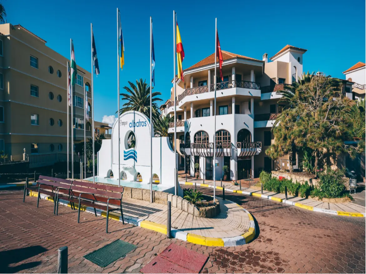 Exterior of Albatros hotel with flags and palm trees.