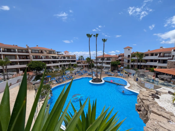 Resort pool area with surrounding buildings and palm trees.