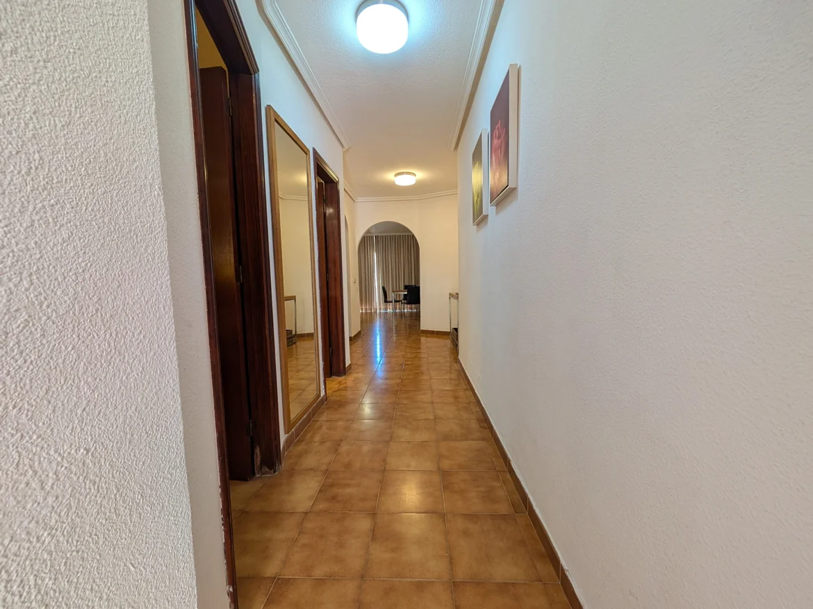 Long hallway with tile floor and bright lights.