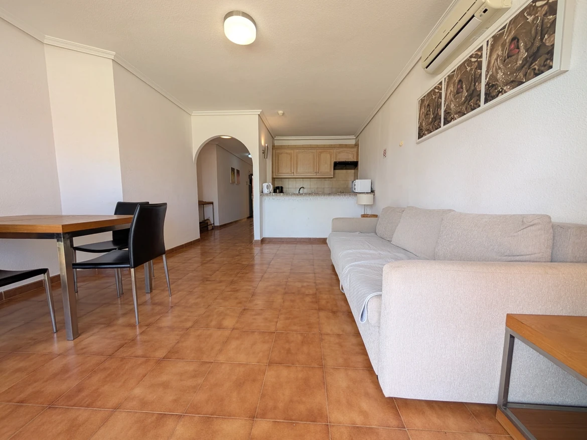 Spacious living room with sofa and dining area.