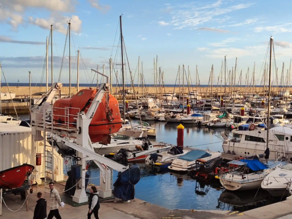Marina with boats and lifeboat in harbor setting.