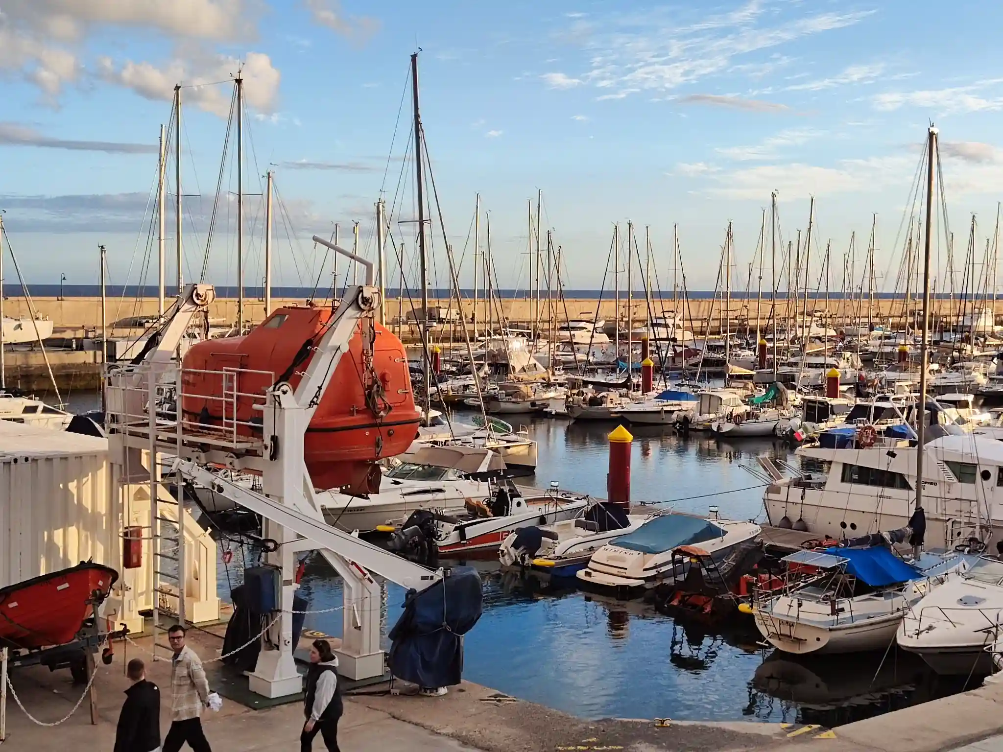 Marina with boats and lifeboat in harbor setting.