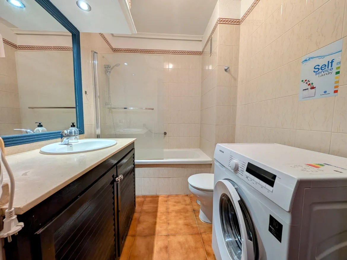 Bathroom with washer, sink, bathtub, and toilet.