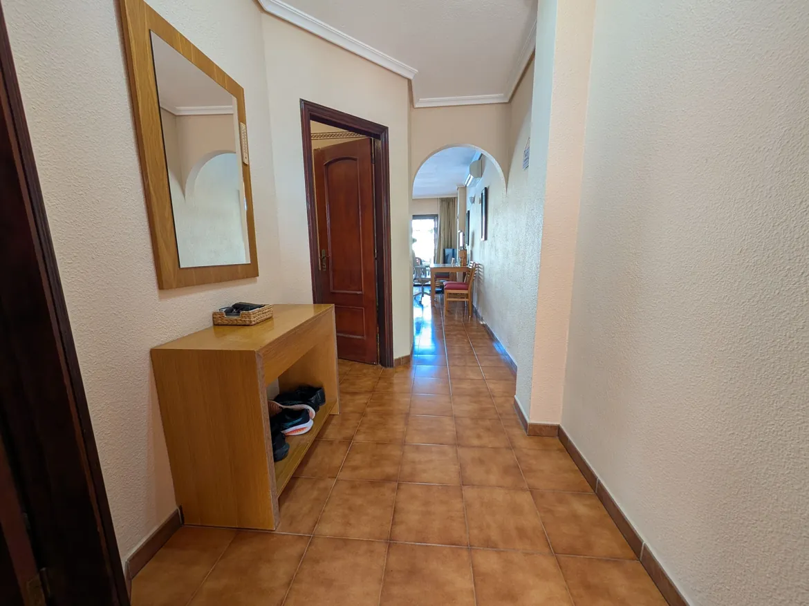 Apartment hallway with mirror and table.