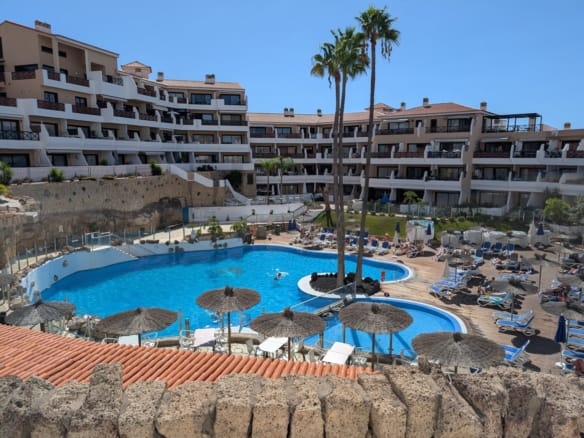 Luxury resort with pool and sunbathing areas.